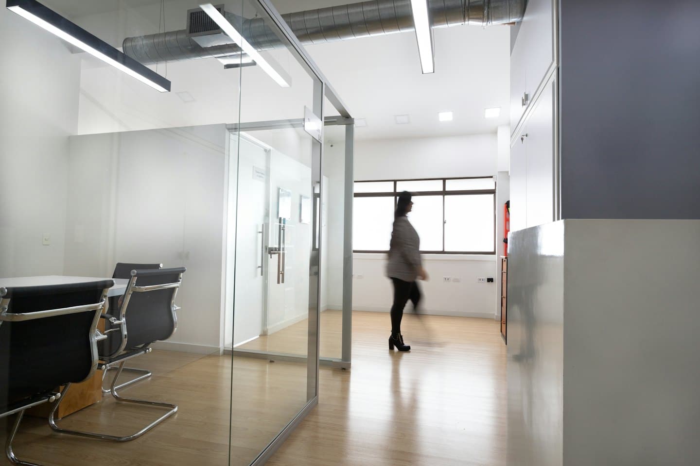 Una persona cammina in un luminoso corridoio di un ufficio moderno.